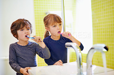 Buy stock photo Shot of a brother and sister brushing their teeth at home