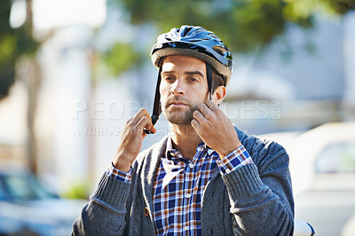 Buy stock photo Shot of a handsome young man preparing to take a ride by putting on a helmet