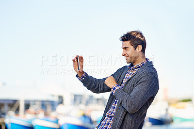 Buy stock photo Man, smartphone and photography at harbor, outdoor and smile by ocean with creativity for web blog. Person, photographer and phone for profile picture, social media or memory by sea port in Cape Town