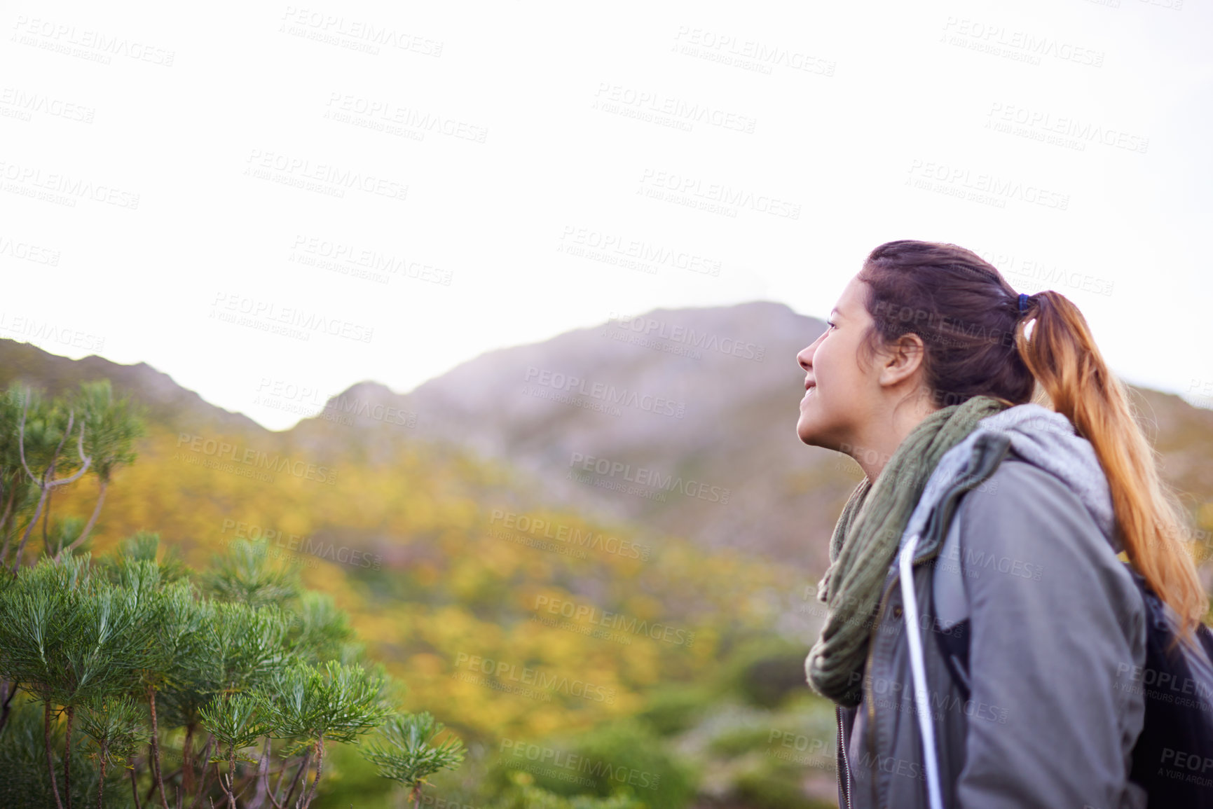 Buy stock photo Woman, smile and hiking for adventure in nature with mountain for walking outdoor for exercise. Young person with backpack and looking for view in landscape with bush and plants in cold season