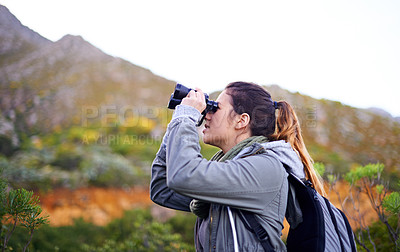 Buy stock photo Shot of an attractive young woman looking through binoculars while on a hike