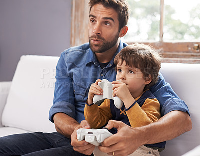 Buy stock photo Gaming, father and son on a sofa, playing and loving at home, quality time and bonding. Family, dad or male child on a couch, controller or playful with fun, relax and connection with joy or cheerful