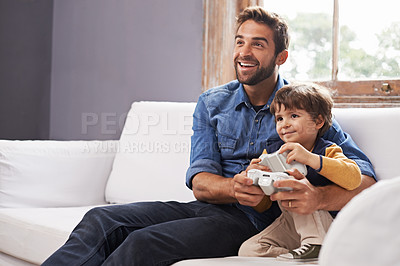 Buy stock photo A handsome father and his cute son playing a video game together