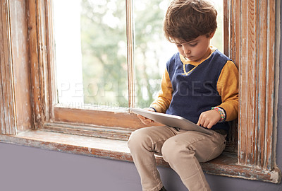 Buy stock photo Home, tablet and serious child on internet, app or game on website for learning by windowsill. Technology, kid and boy in house for education, relax and watch cartoon online on digital electronics