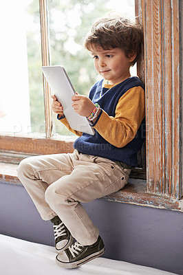 Buy stock photo Home, tablet and young kid on app, internet and game on website for learning by windowsill. Technology, child and boy in house for education, relax and watch cartoon online on digital electronics