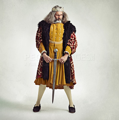 Buy stock photo Studio shot of a richly garbed king holding a sword suggestively