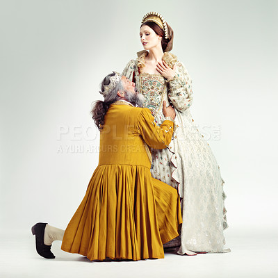 Buy stock photo Studio shot of a king kneeling and embracing his queen's waist