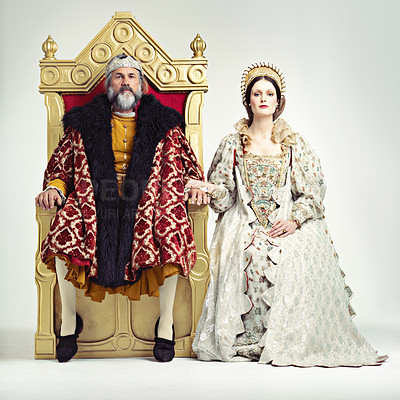 Buy stock photo Studio shot of a king and queen sitting on thrones