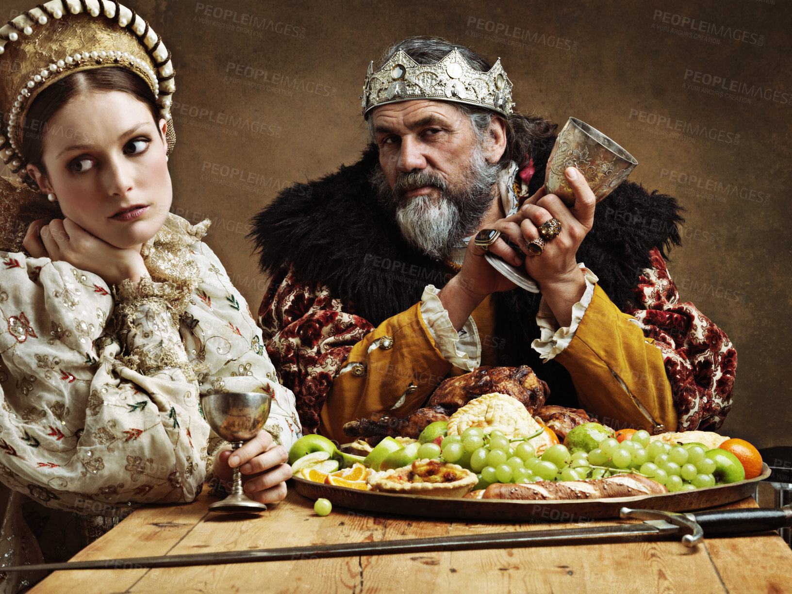 Buy stock photo King, queen and portrait with feast at table for fine dinning in royal banquet, vintage and majestic with crown. Monarch, husband and bored together with alcohol for buffet for formal celebration.