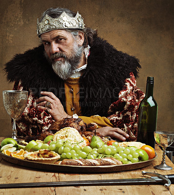 Buy stock photo King, confident and feast in table with wine as royalty on dining hall for tradition, culture and meal in palace. Portrait, monarch and leader with eating buffet or supper with sword for chicken