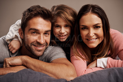 Buy stock photo Portrait of a happy family lying on a bed