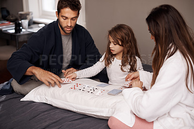 Buy stock photo Parents, girl and fun with playing cards for game for bonding, learning and relax with strategy in bedroom. Father, mother and daughter with deal, maths and teaching with connection in family house