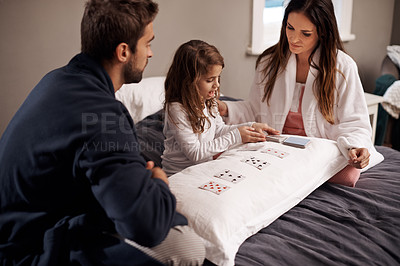Buy stock photo Parents, girl and child with playing cards in bedroom for bonding, learning and relax with love in house. Father, mother and daughter with games, maths and teaching with connection in family home