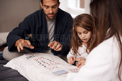 Buy stock photo Mom, father and girl with playing cards for competition with bonding, learning and relax with strategy in bedroom. Dad, mother and daughter with deal, deck and child on bed with game in family house