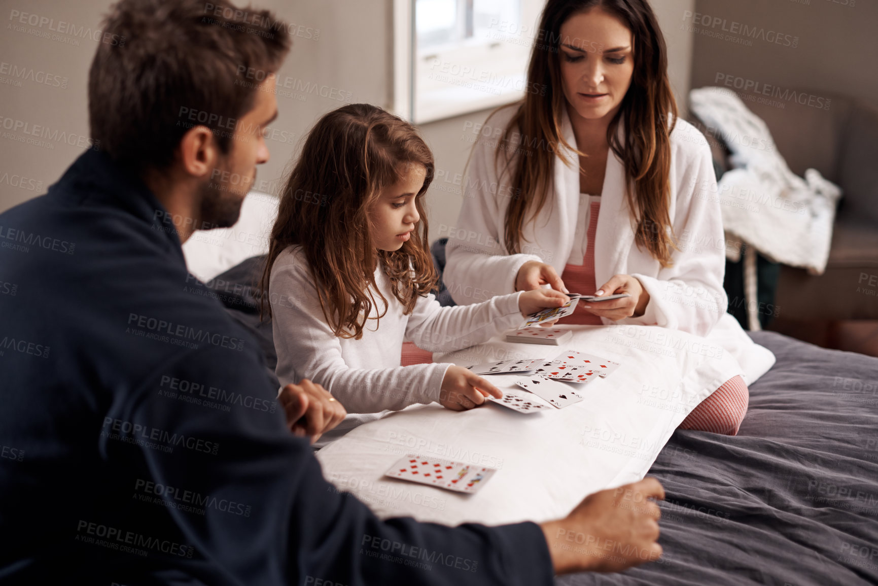Buy stock photo Shot of a young family playing cards together at home