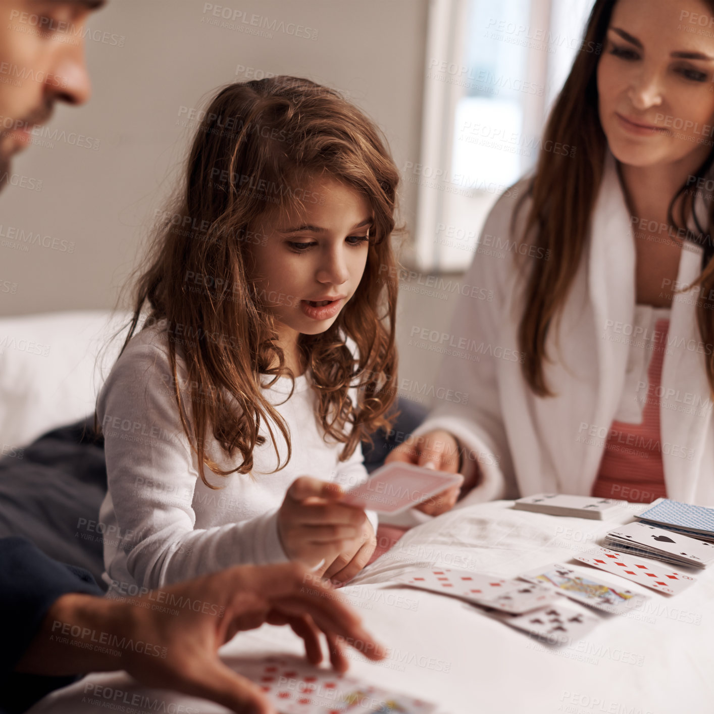 Buy stock photo Parents, girl and fun of playing cards in home for bonding, learning and relax with strategy in bedroom. Father, mother and daughter with games, maths and teaching with connection in family house