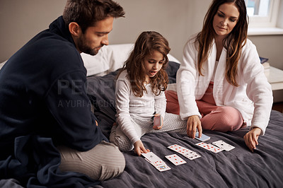 Buy stock photo Mom, dad and girl with playing cards to relax in home with bonding, learning or fun with strategy in bedroom. Father, mother and daughter with games, maths or teaching with connection in family house