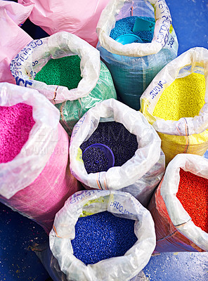 Buy stock photo Bag, color and plastic resin with recycling for dye, manufacturing or ecology on floor in factory. PVC pellets, industry and molecule for polymer at plant for storage, particle and above in warehouse