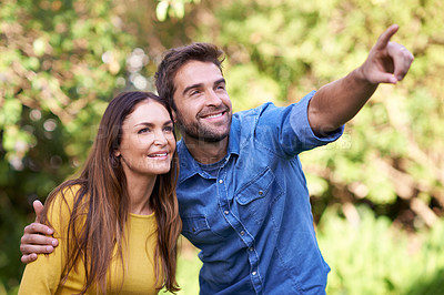 Buy stock photo Happy couple, women and man pointing in nature or park for bonding, dating and relationship with smile. People, love and romantic in backyard or outdoor with joy, excited and commitment in marriage