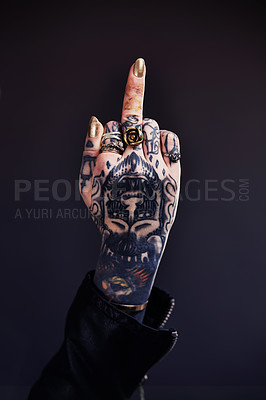 Buy stock photo Shot of a tattooed woman giving the finger to the camera