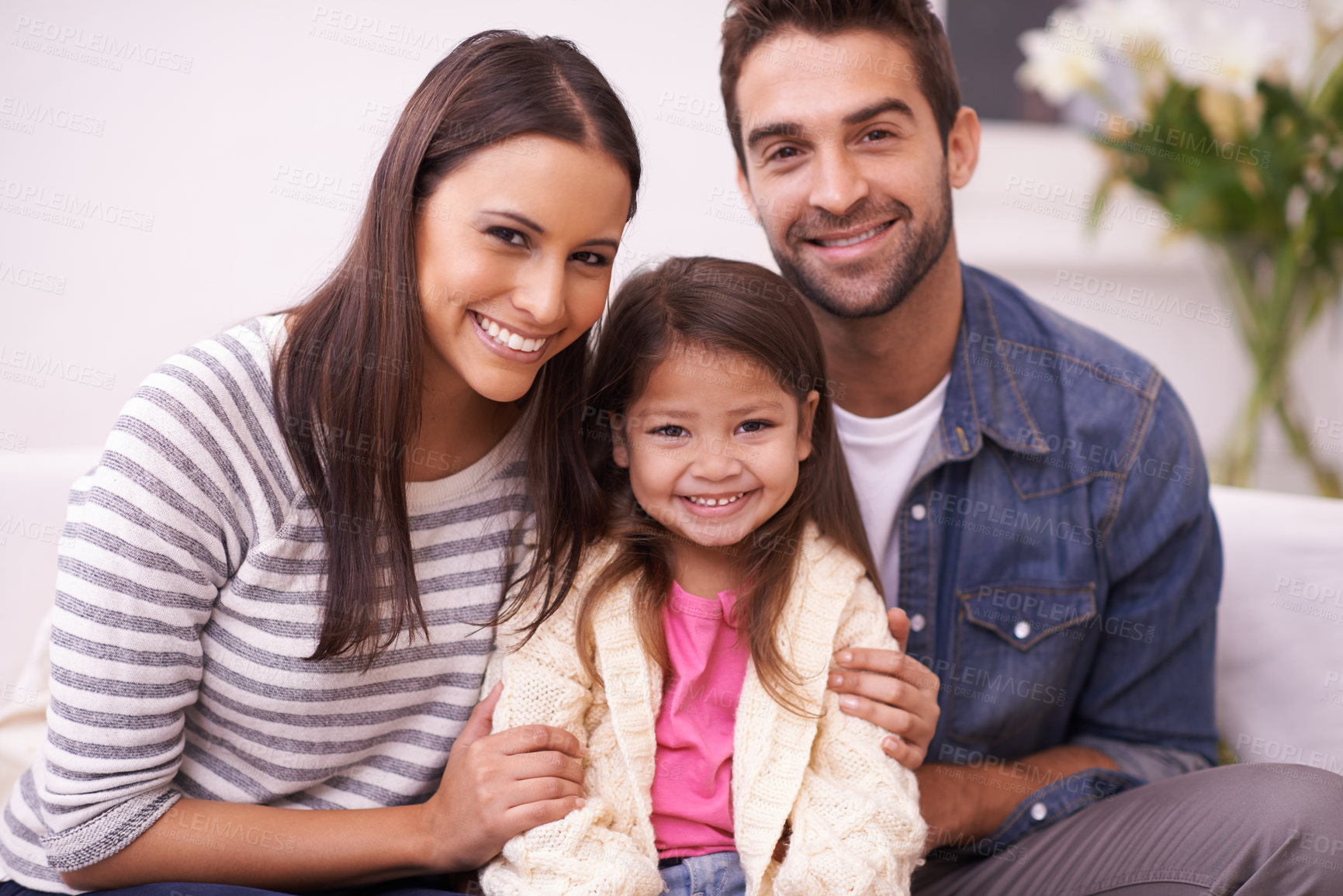 Buy stock photo Portrait of a happy young family sitting together at home