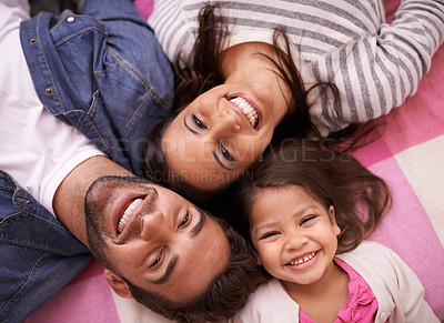 Buy stock photo High angle portrait of a happy young family lying on their backs at home
