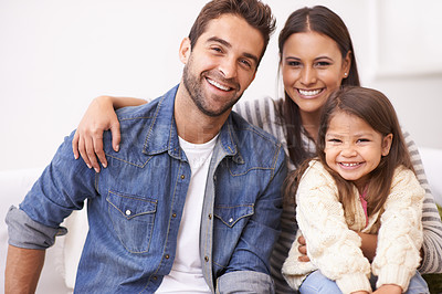 Buy stock photo Portrait of a happy young family sitting together at home
