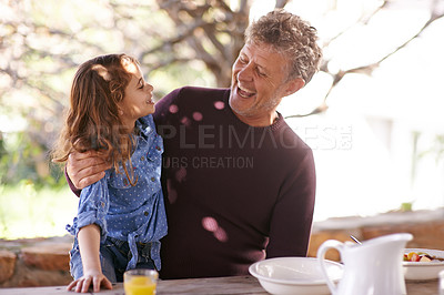 Buy stock photo Shot of a little girl and her grandfather having breakfast together outside