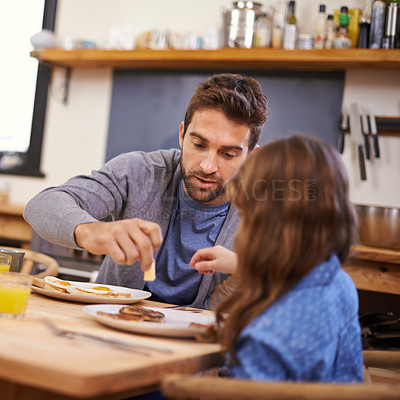 Buy stock photo Shot of a little girl eating breakfast with her dad in the kitchen