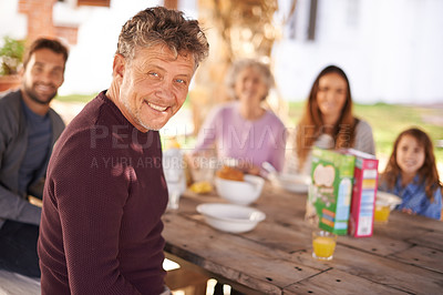 Buy stock photo Portrait, mature and man with family for picnic outdoor in nature of backyard of house, smile and joy. Women, men and child eating breakfast on table of wood in summer, happiness and love in home