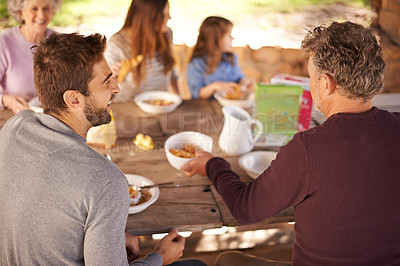 Buy stock photo Outdoor, women and men with family for picnic in nature of backyard of house, smile and joy. Group of people and child eating breakfast on table of wood in summer, happiness and love together in home