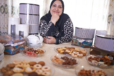 Buy stock photo Mature woman, Islamic and food in house with cheerful, smile and dining table for Iftar. Muslim person, cookie dessert and joy with Eid Mubarak, religion and celebration for breaking fast at home

