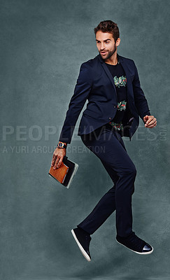 Buy stock photo Brazilian man, suit and jumping in studio with notebooks, fashion and joy on grey background. Male model, dance and classy apparel for mockup space, isolated, confident and stylish businessman