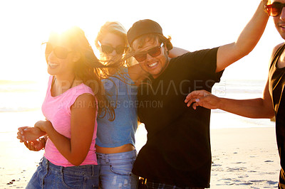 Buy stock photo Shot of a group of friends walking along a beach at sunset