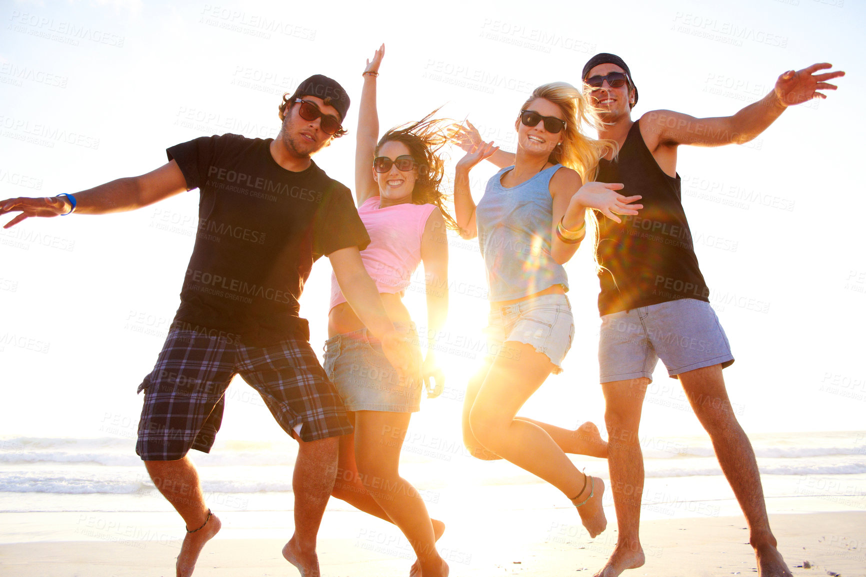 Buy stock photo Shot of a group of friends walking along a beach at sunset