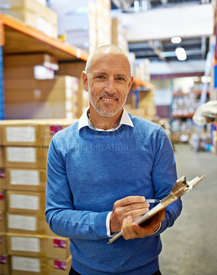 Buy stock photo A warehouse employee standing with a clipboard beside shelving filled with boxes