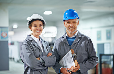 Buy stock photo Two people wearing hardhats smiling at the camera in a factory