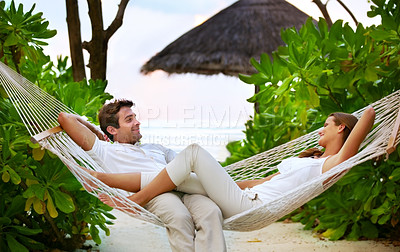 Buy stock photo Shot of a happy couple relaxing on a hammock together in their own private paradise - Romance