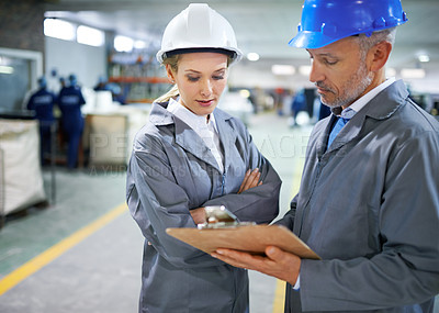 Buy stock photo Man, woman and discussion with clipboard in factory for quality inspection or safety checks and process monitoring. Team, communication and board for manufacturing information in printing warehouse.