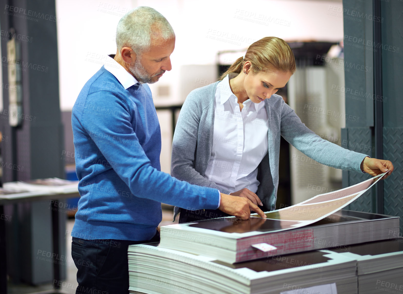 Buy stock photo Two publishers assessing the quality of printed work in a factory