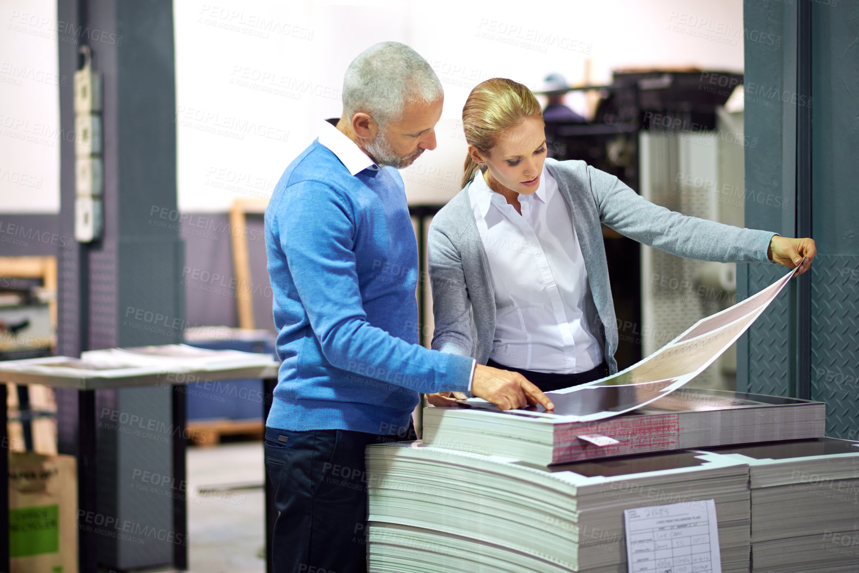 Buy stock photo Two publishers assessing the quality of printed work in a factory