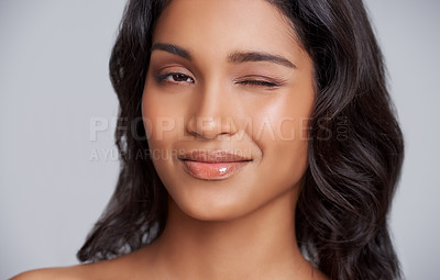 Buy stock photo Woman, face and wink with beauty and skincare glow, playful and fun with lip gloss for moisturizer on grey background. Flirt in portrait, natural cosmetics and hair care with wellness and dermatology