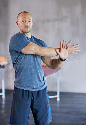 Buy stock photo A cropped shot of a handsome trainer stretching before a workout session