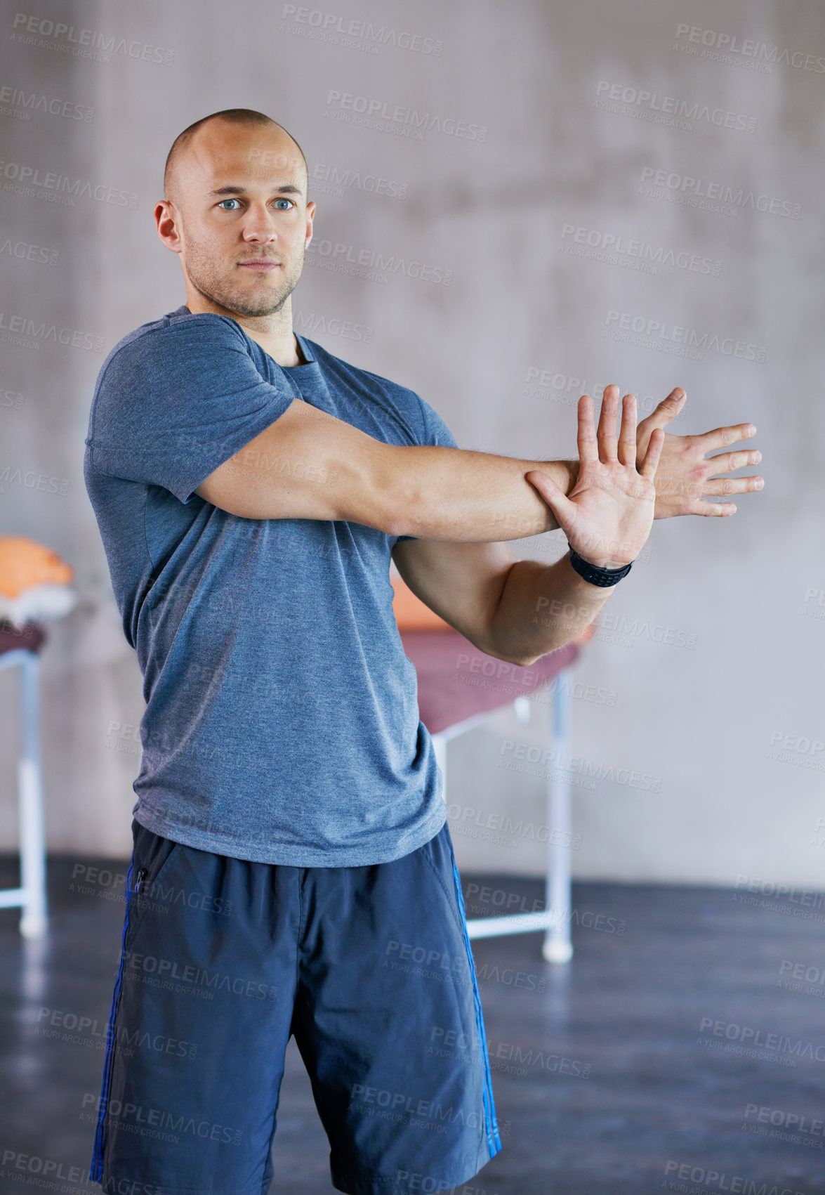 Buy stock photo A cropped shot of a handsome trainer stretching before a workout session