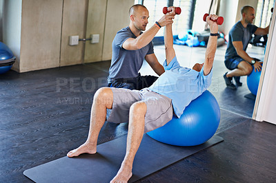 Buy stock photo Shot of a physiotherapist helping an elderly man with dumbbells