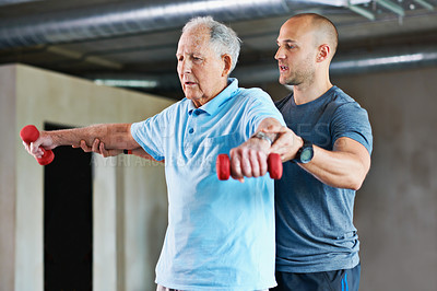 Buy stock photo Shot of a physiotherapist helping a senior man with weights