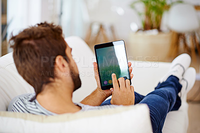 Buy stock photo Rearview of a man using his tablet on his couch