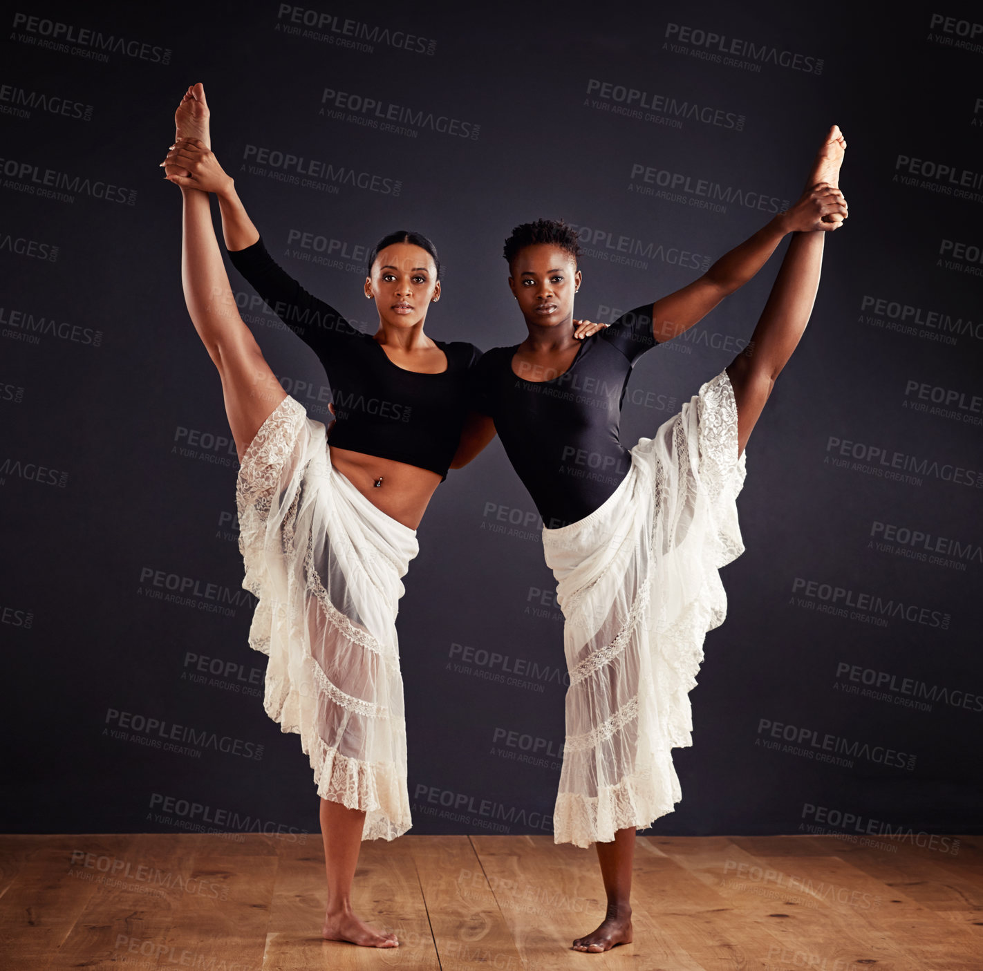 Buy stock photo Two young female contemporary dancers using a soft white white skirt for dramatic effect