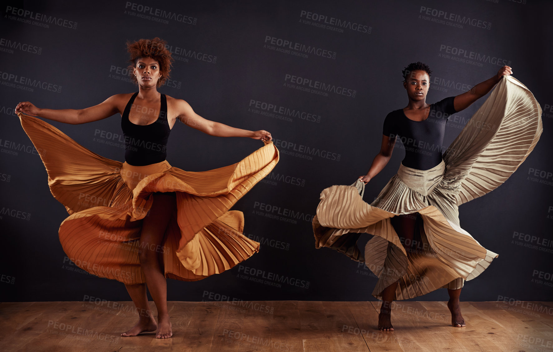 Buy stock photo Two contemporary dancers with flowing skirts in front of a dark background