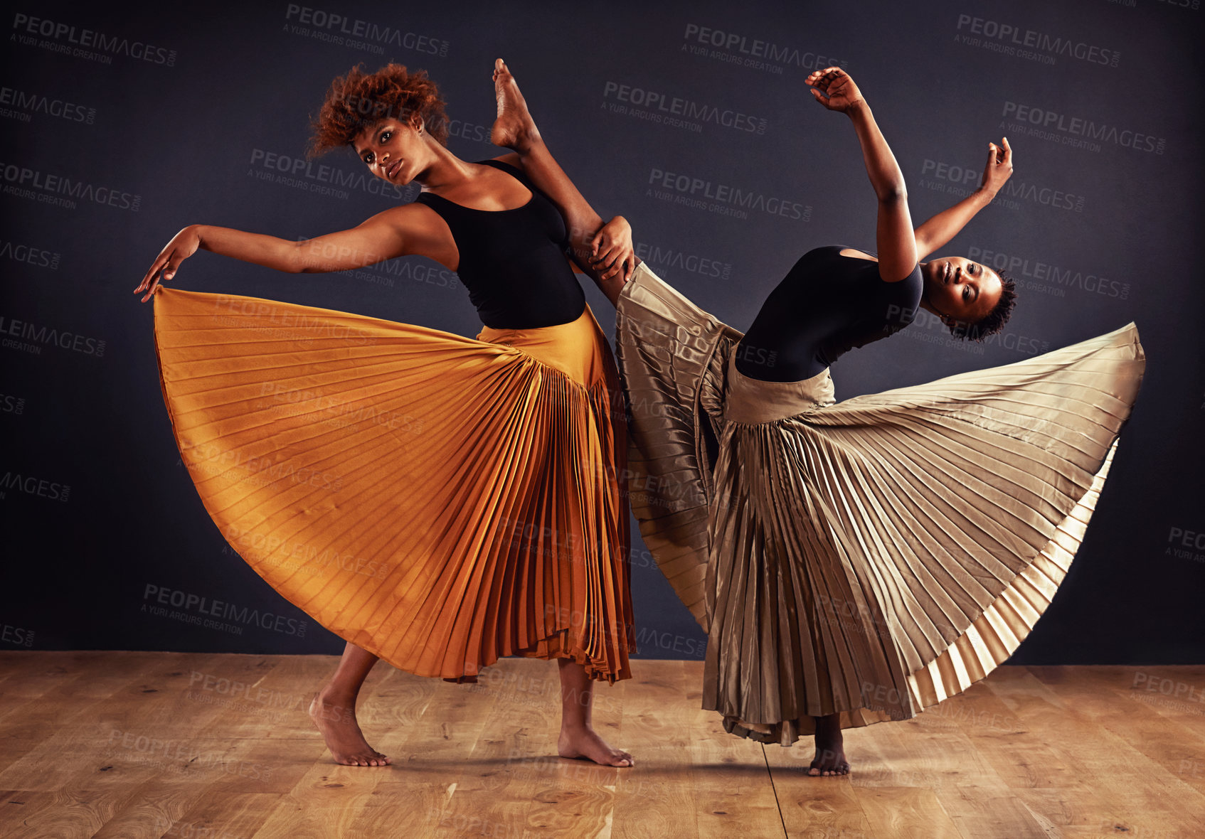 Buy stock photo Two contemporary dancers with flowing skirts in front of a dark background